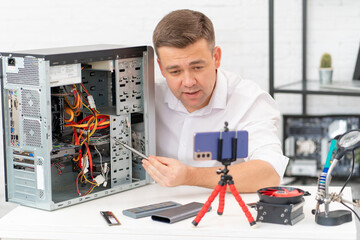 a man records a video lesson on computer repair or makes an online consultation.