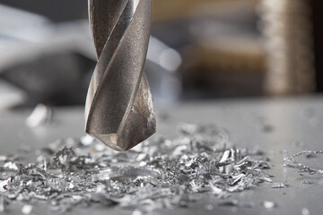 metal drill bit make holes in aluminium plate on industrial drilling machine. Metal work industry.