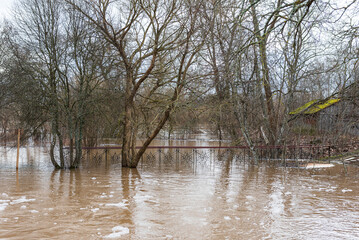 Flooded pedestrian bridge and trees in spring day, Ranki, Latvia.