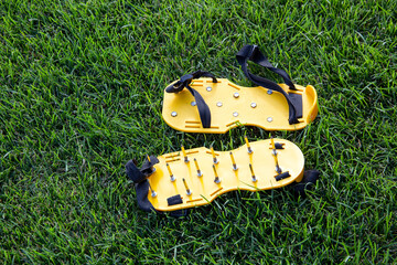 Yellow lawn aerator sandals with nails for lawn cultivation. Shoes with aeration spikes for...