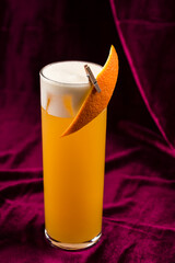 orange cocktail with orange on red velvet