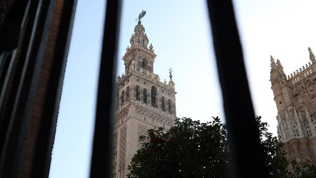 The Giralda tower in Seville through the grille of the entrance door to the Patio de los Naranjos.