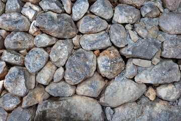 Wall of large rough gray stones, texture. Rock wall background