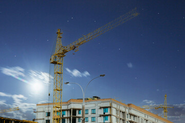 lifting construction crane on the construction of a residential complex against the background of the night sky.