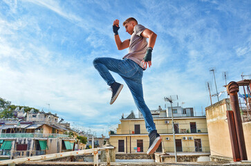 Fitness Model Fighter doing Muay Thai Kickboxing Flying Knee under the blue sky.