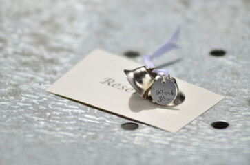 Close-up of silver bells and a thank you tag on a reserved card