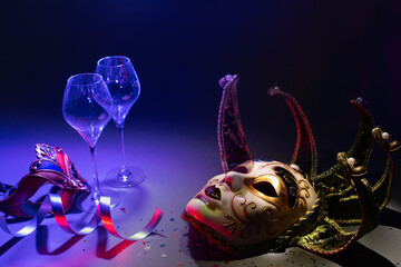 Venetian carnival masks with champagne glasses and ribbons in dark environment