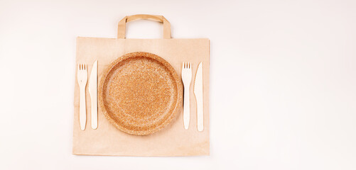 Eco craft paper tableware,cups,fast food containers.Recycling,eco-friendly concept.Disposable eco cutlery,plates,spoons,knives,forks on a light background.Craft paper bag for food delivery.Copy space.