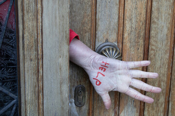 domestic violence, asking for help, a woman's hand makes a sign asking for help from a closed door,...