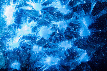 Photo of blue toned frozen cracked and damged ice surface texture.