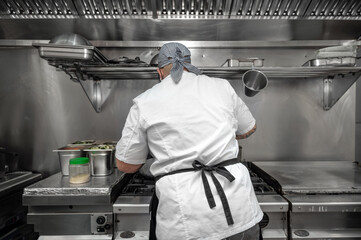 Back view of woman chef cooking food in the kitchen of a restaurant. High quality photography.
