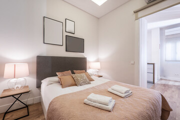 Bedroom with king size bed with pink bedspread, matching cushions, headboard upholstered in gray...