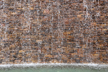 Stone Wall with Water Falling Down it into Fountain