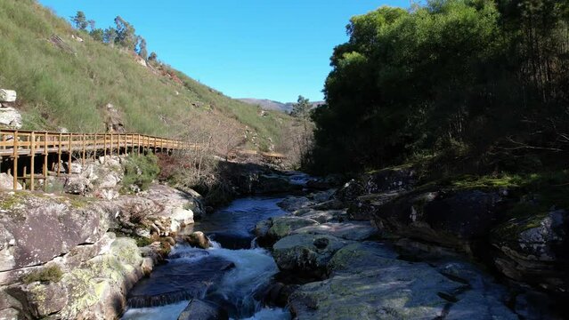 DRONE AERIAL FOOTAGE - Wooden pathway across the Valdevez Land. The pathway develops itself along the rivers Lima and Vez. The river hiking trail Ecovia do Vez near Arcos de Valdevez, Portugal.