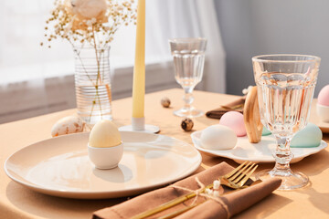 Background image of single Easter egg plated on elegant dinner table decorated for Spring in sunlight, copy space