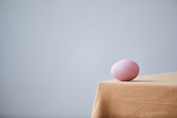 Minimal shot of single Easter egg placed on cozy dinner table, graphic Spring background, copy space