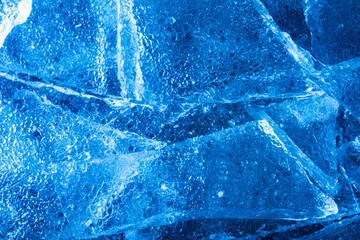 Photo of blue toned frozen cracked ice pieces surface texture.