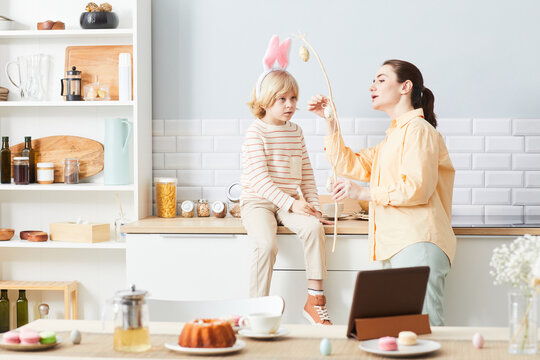 Portrait of young woman decorating house for Easter with cute little boy wearing bunny ears, copy space - Powered by Adobe