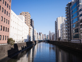 modern buildings and blue sky reflected on the river water surface in tokyo