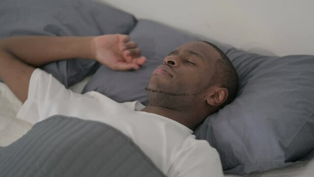 African Man Laying in Bed Unable to Sleep