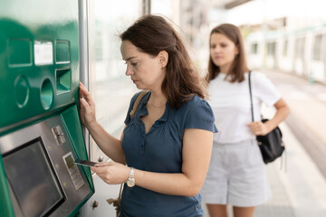 Fototapeta na wymiar Nice woman traveler buying ticket in subway at ticket vending machine. High quality photo