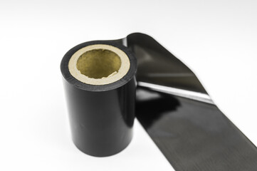 Black thermal transfer ribbon - TTR. Wax thermo ribbon on cardboard reel for barcode. Supply material for printing industry. Selective focus, isolated on white