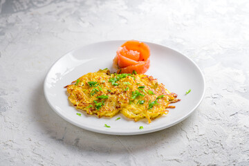 Fried potato pancakes with salted salmon on white plate