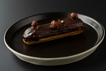 dessert is a small puff pastry pie with stuffing inside on a black serving plate on a black background . A piece of cake with a cut