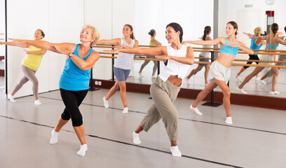 Fototapeta na wymiar Group of dancers exercising modern dance movements in large ball room