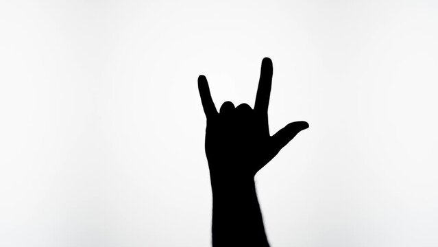 Man showing rock and roll gesture with fingers isolated on white background. Male person making shadow silhouette with hand close-up.