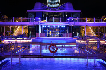Cruise ship swimming pool at night on the top deck with scenic views.