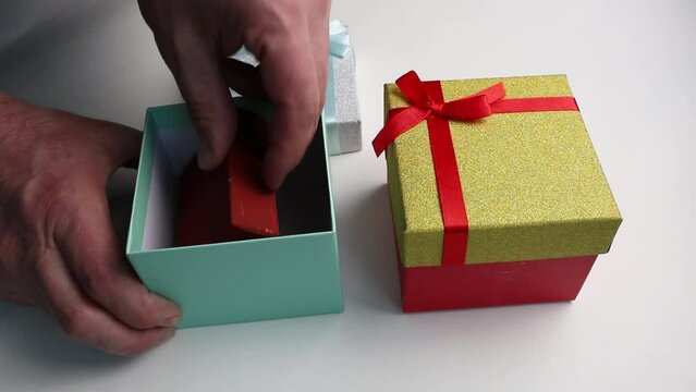 Men's hands open red and blue gift boxes and take out red boxes with surprises.
