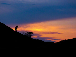Man on top of a mountain looking at the sunset