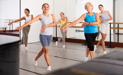 Dancing active women engaged in a group class practice energetic dance in a modern dance studio