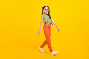 Photo of pretty adorable preteen girl dressed green top walking smiling isolated yellow color background