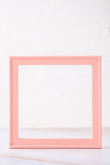 pastel pink picture frame with olive leaf on marble table with concrete wall