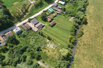 Aerial landscape view of green cultivated agricultural fields with growing crops and distant village houses