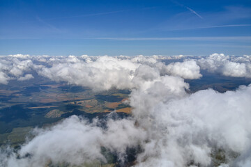 Aerial view from airplane window at high altitude of earth covered with white puffy cumulus clouds