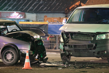 Cars crashed heavily in road accident after collision on city street at night. Road safety and insurance concept