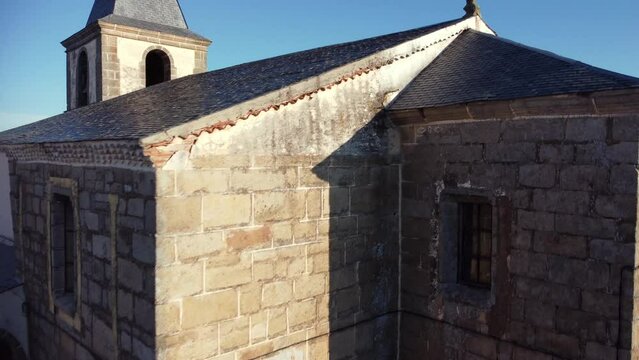 Rotating aerial drone shot of reformed visigoth church in a rural village of Zamora, Castilla y Leon, Spain. Clear day with no clouds, beautiful summer morning in a small village with brown roofs.