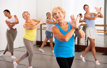 Fototapeta na wymiar Active women engaged in dancing at a group training session in the studio practice modern energetic dance