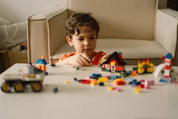 Fotobehang Lego Cute boy is playing constructor at home. Kid playing block toys in home at nursery. Toddler having fun and building out of bright constructor bricks. Development and Construction Concept  © Анастасія Стягайло