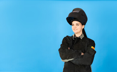 A female welder in a protective mask and a welder's suit on a blue background