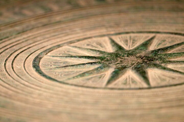 Ancient stone carving relief design image, compass or a star motif. Closeup macro photograph. 古代の羅針盤や日時計、星を思わせる文様の石と銅のタイルをマクロ接写撮影。