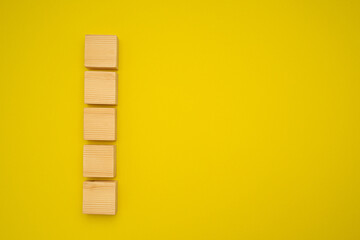 Top view of blank five wooden cubes on a yellow background