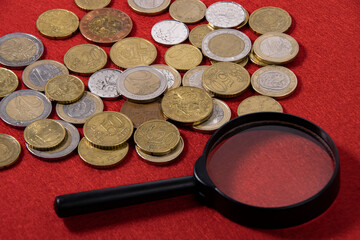 Collection of European coins and collector magnifying glass on red