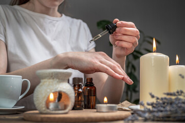 Woman is smearing her hands with a natural organic oil. Aroma lamp with essential oils and candles...