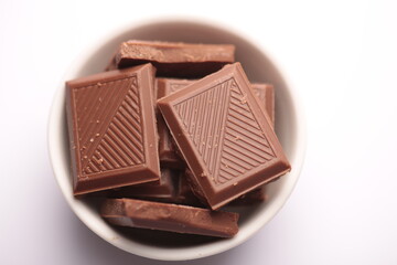 Milk chocolate pieces isolated on white background from top view