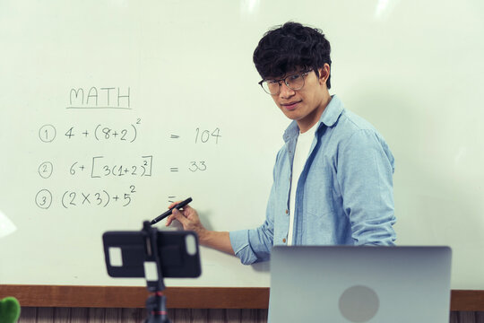 Teacher explaining the numbers on the board while video calling with students studying online.