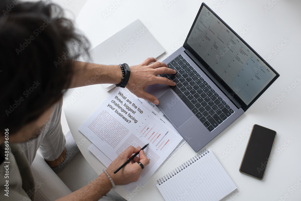 Aufkleber Contemporary auditor or analyst looking through text in document and analyzing financial data on laptop screen while working from home